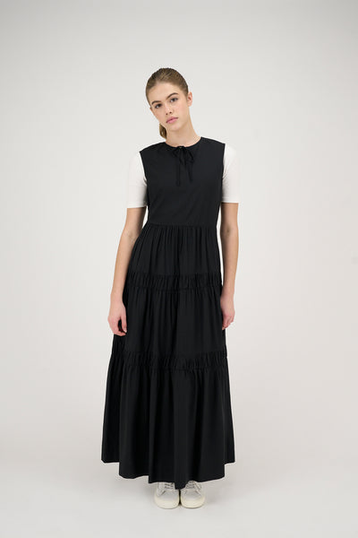 Woman wearing a black tiered jumper with a white top on a white background