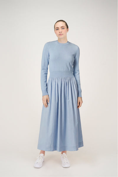 Woman wearing a light blue dress with long sleeves on a white background